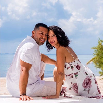 Alumni couple Fernando & Cynthia pose on a beach for a photo 