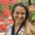 nicole elyse feldman looking at the camera smiling in front of red flowers