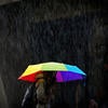 Person walking in rain using rainbow umbrella