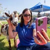 Staff taking selfie with goat outdoors.