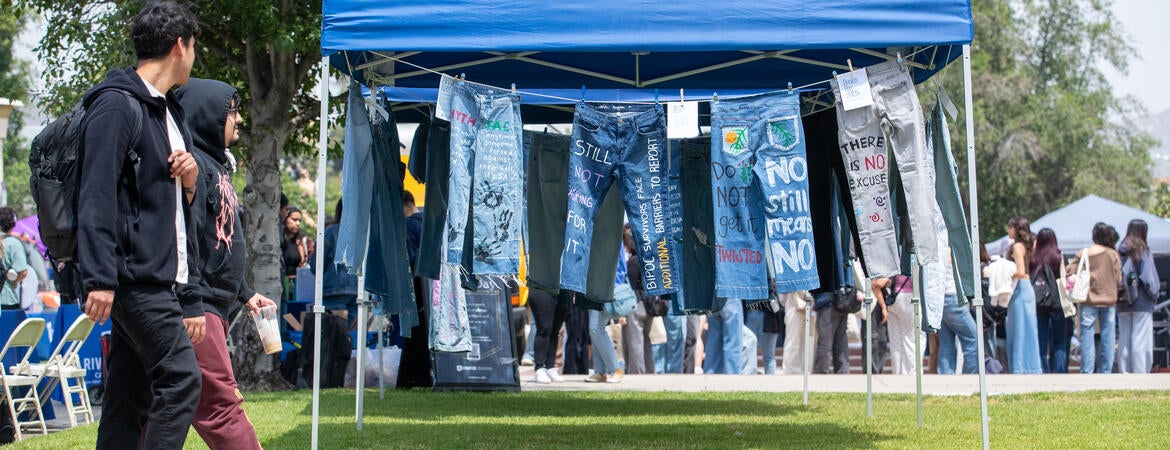Students walking by hanging jeans painted with supportive statements