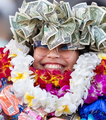 Graduate covered in floral leis and money crown