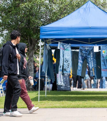 Students walking by hanging jeans painted with supportive statements