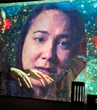 Photo of video projection of actress Rinska Carrasco in a performance of "I Hear America Singing."