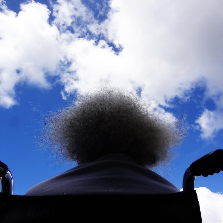 A person sitting in a wheelchair with the sky above