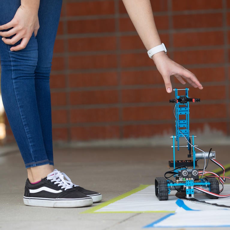 A student works with a small blue robot they built