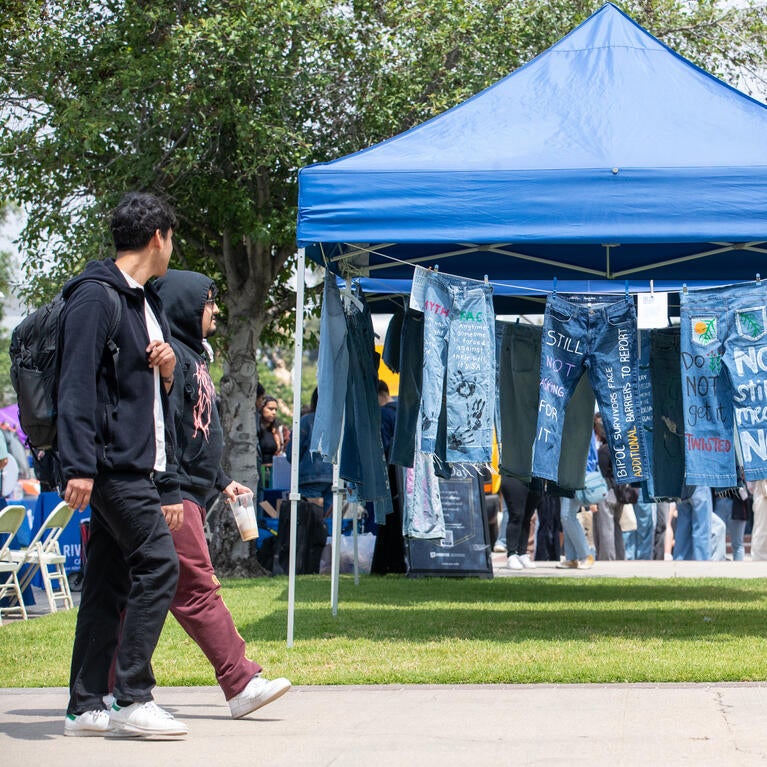 Students walking by hanging jeans painted with supportive statements