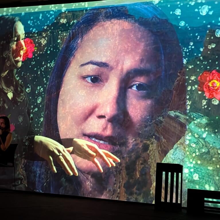 Photo of video projection of actress Rinska Carrasco in a performance of "I Hear America Singing."