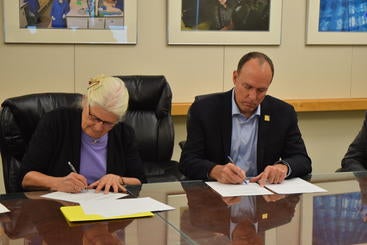 Nora Hackett, left and Dean Lynch sign an endowment agreement.