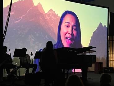 Photo of video projection of actress Rinska Carrasco in a performance of "I Hear America Singing."