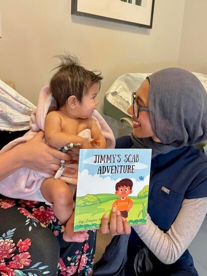 Zayan Musa with her book and a baby