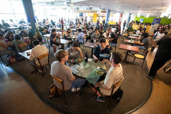 Busy HUB food court with students eating and socializing at tables.