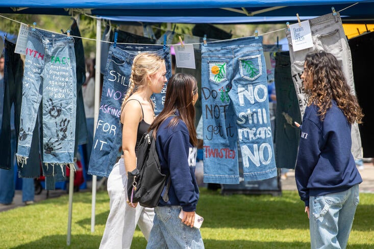 Students looking at jeans painted with statements on Denim Day
