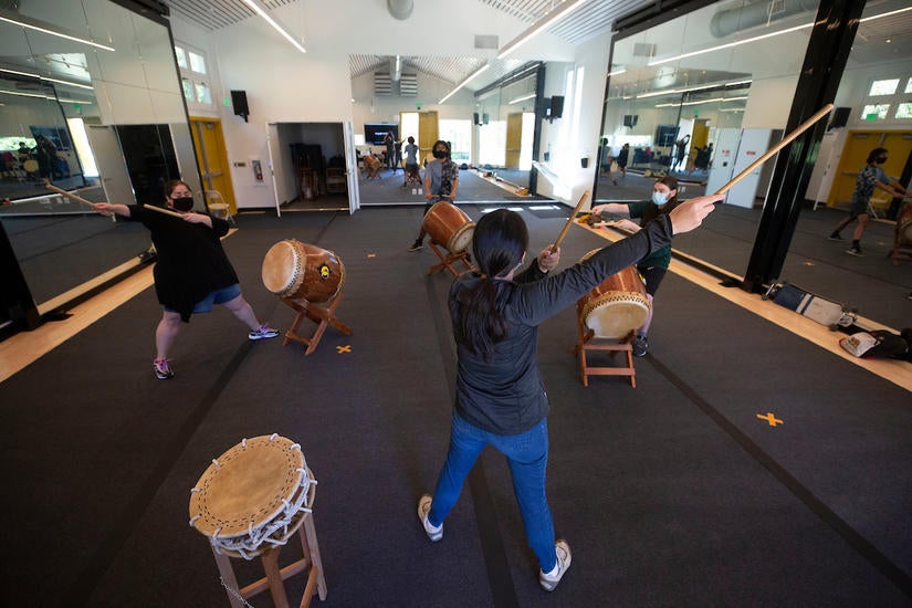 Music lecturer Terry Nguyen works with students in their Taiko Drum class on Tuesday, March 2, 2021, in the Barn Theater at UC Riverside. The class was able to continue during the pandemic with part of the students watching online while others participated in-person.  (UCR/Stan Lim)