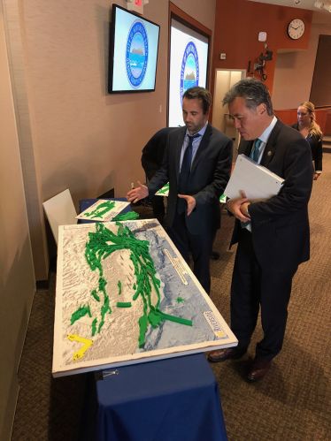 EQ risk Christos Kyriakopoulos standing near display with Mark Takano.